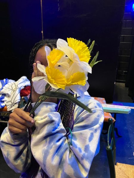 Jasmyn Benedict pictured with a prop flower from costuming, in the backstage area of the auditorium