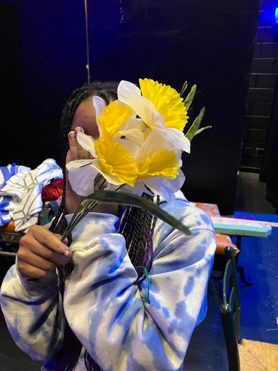 Jasmyn Benedict pictured with a prop flower from costuming, in the backstage area of the auditorium